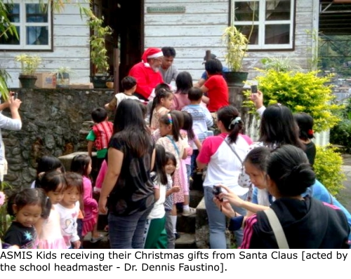 ASMIS Kids receiving their Christmas gifts from Santa Claus [acted by the school headmaster - Dr. Dennis Faustino].